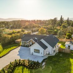 an aerial view of a house in the middle of a green yard with trees and grass