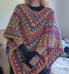 a woman is wearing a crocheted shawl and holding her hand on her hip