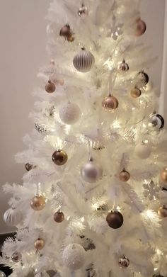 a white christmas tree with gold and silver ornaments