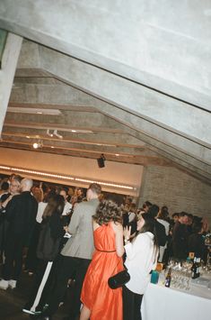 a group of people standing around in a room full of wine glasses and bottles on tables