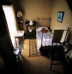 a bed room with a neatly made bed next to a chair and table in front of a window