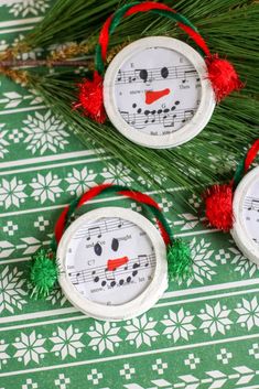 three snowman ornaments are sitting on a green and white tablecloth with red pom - poms