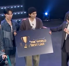 three young men standing next to each other holding up a sign that says the world best lar