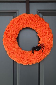 an orange wreath with a black spider on it is hanging from the front door,