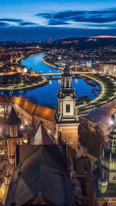 an aerial view of a city at night with lights on and water in the background