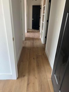 an empty hallway with white walls and wood flooring is seen in this image from the front door