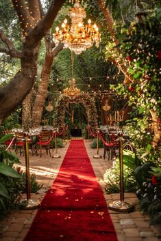 a red carpet is on the ground in front of tables and chairs with chandeliers hanging from them