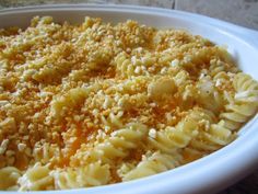 a bowl filled with macaroni and cheese covered in crumbs on top of a table