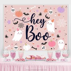 there is a pink table with halloween decorations on it and the words hey boo written in black