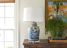 a blue and white vase sitting on top of a wooden table next to a lamp