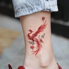 a woman's foot with a red bird tattoo on the side of her leg