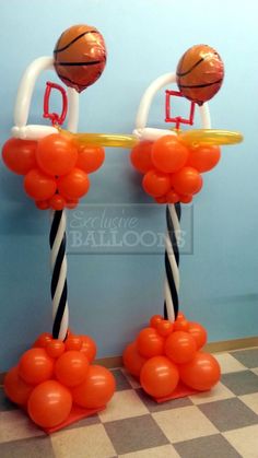 two basketballs are on top of some orange and white balloons in the shape of hoop