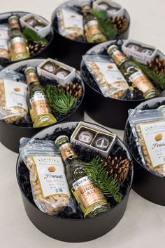 four black trays filled with wine bottles and pine cones