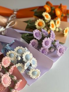 crocheted flowers are arranged on top of folded paper and scissors in the background