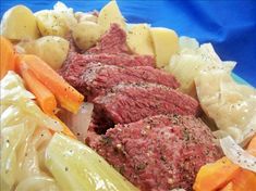 meat, potatoes and carrots on a plate with blue cloth in the back ground