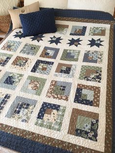 a bed with a blue and brown quilt on it's headboard next to a pillow