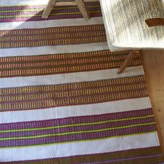 a table and chair sitting on top of a wooden floor next to a striped rug