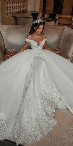 a woman in a white wedding dress sitting on a couch and posing for the camera