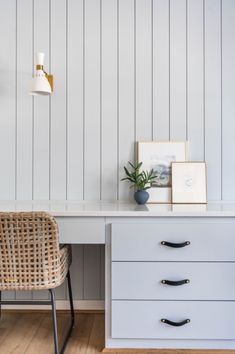 a white desk with two drawers and a wicker chair in front of the desk