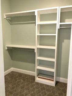 an empty walk in closet with white shelving and gray carpeted flooring on the walls