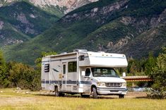 an rv parked on the side of a road in front of some mountains and trees