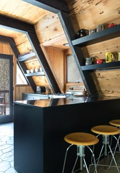 an open kitchen area with stools next to it