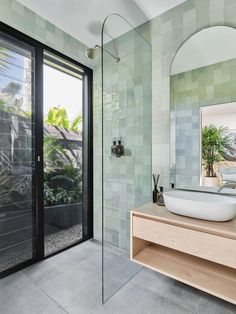 a bathroom with a sink, mirror and glass door leading to the outside patio area