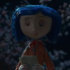 an animated doll with blue hair holding a cell phone in front of a large crowd