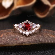 a red and white ring sitting on top of a piece of wood next to flowers