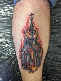 a tattoo on the leg of a man with flames around him and a church in the background