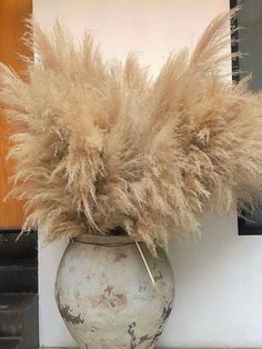 a vase filled with dry grass sitting on top of a table