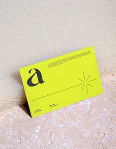 a yellow business card sitting on top of a white counter next to a black object