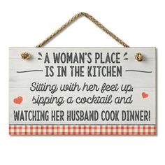 a woman's place is in the kitchen sign hanging from a rope on a wall