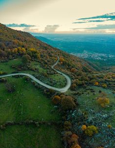 an aerial view of a winding road surrounded by trees in the fall with colorful foliage