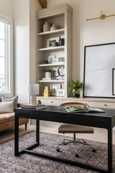 an office with a desk, chair and bookshelf in front of a window