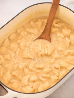 a wooden spoon in a pot filled with macaroni and cheese