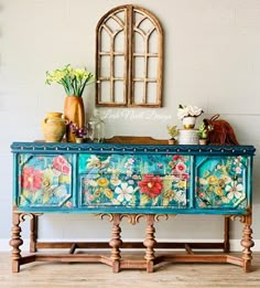 an old dresser with flowers painted on it and vases sitting on top of it