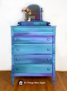 the dresser is painted blue and has flowers on it