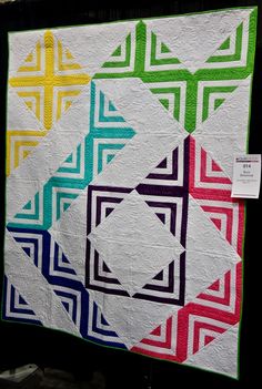 a colorful quilt hanging on the wall in front of a black background with a price tag