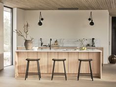 two stools sit in front of an island with marble countertops and wooden cabinets