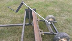 an old trailer sitting in the grass with two wheels on it's side and one wheel missing