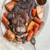 a white plate topped with meat and carrots next to a bowl of dipping sauce