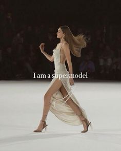 a woman walking down a runway in a white dress