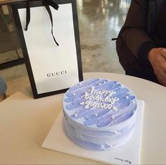 a blue birthday cake sitting on top of a white table next to a black bag