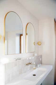 a bathroom sink with two mirrors above it