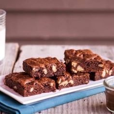 some brownies are sitting on a white plate and next to a glass of milk