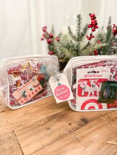 two plastic containers filled with christmas treats on top of a wooden table next to a potted plant