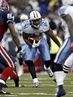 a football player running with the ball in his hand and other players on the field behind him