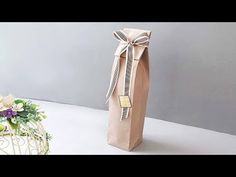 a brown paper bag with a bow on it next to some flowers and a basket