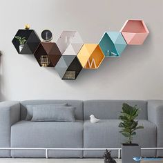 a living room with a gray couch and colorful hexagonal shelves on the wall